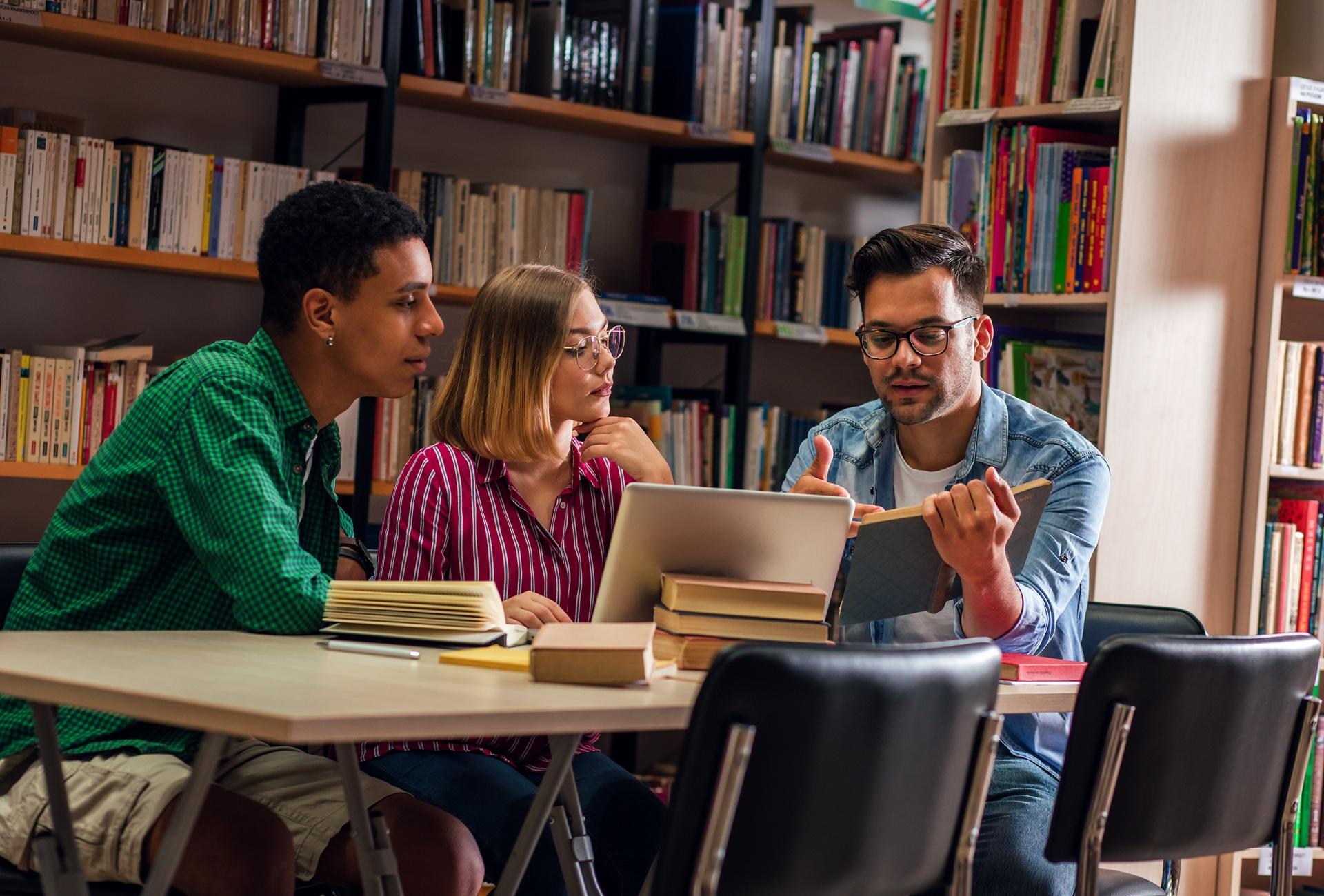 Studierende arbeiten gemeinsam am Tisch mit Büchern | Ghostwriter Hausarbeit