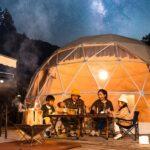 Familie sitzt beim Glamping am Tisch unter Sternenhimmel | Petroleum